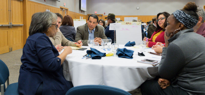 A group of faculty sit around a table having a discussion during a workshop