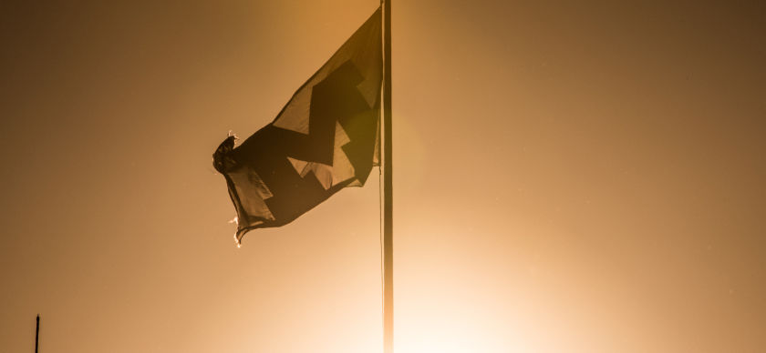 A U-M flag backlit by the bright sun
