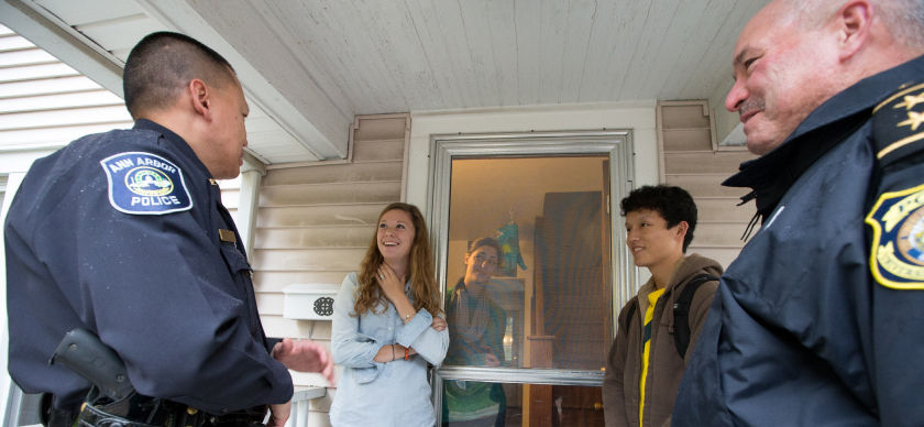 Police officers speak with two students on their front porch